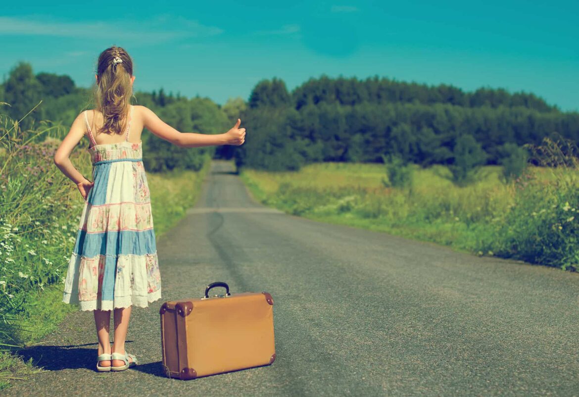 Little,Girl,With,Vintage,Suitcase,On,Rural,Road.